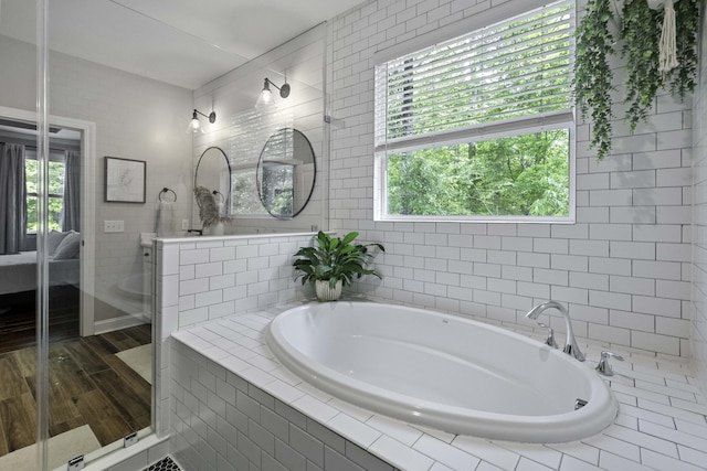 bathroom featuring wood finished floors, a garden tub, and a stall shower