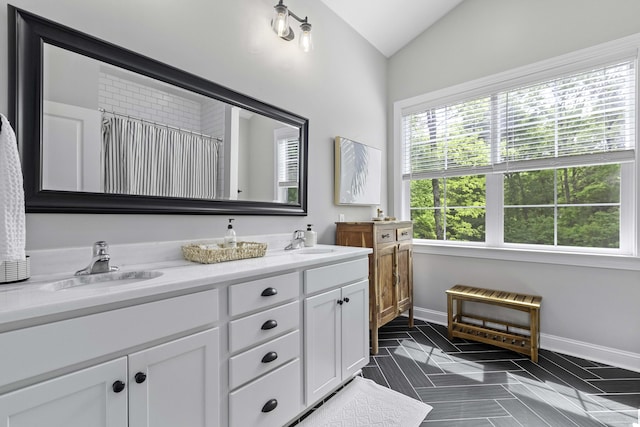 full bathroom with a sink, a healthy amount of sunlight, and vaulted ceiling