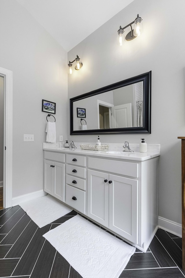 full bathroom featuring double vanity, a sink, and baseboards