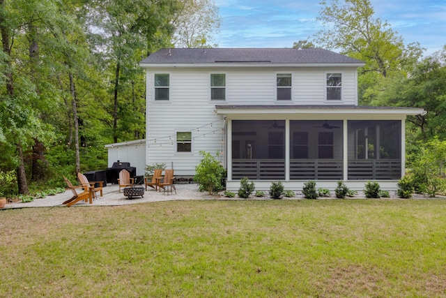 rear view of house featuring a shingled roof, an outdoor fire pit, ceiling fan, a sunroom, and a lawn