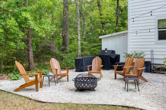 view of patio with an outdoor fire pit, grilling area, and a wooded view