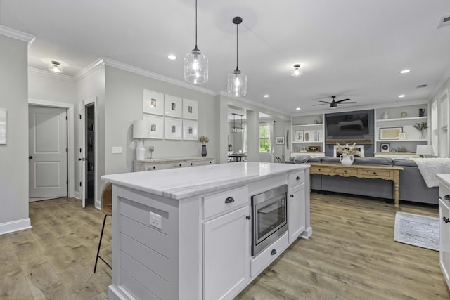 kitchen featuring crown molding, ceiling fan, white cabinetry, stainless steel microwave, and recessed lighting