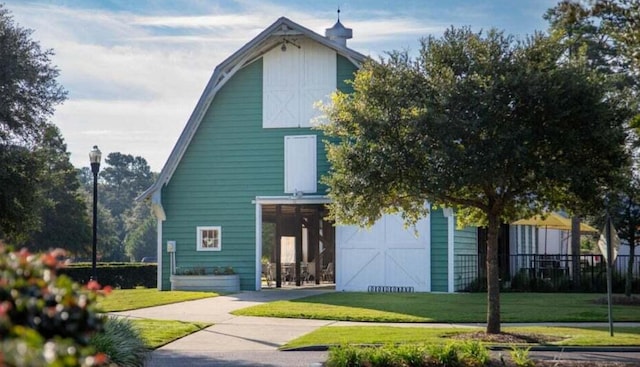 back of property featuring a barn, a garage, a lawn, and an outbuilding