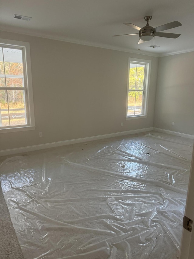 empty room featuring ornamental molding, visible vents, and baseboards