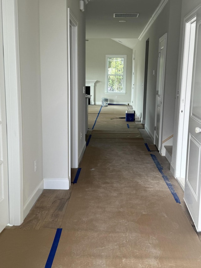 hallway with ornamental molding, visible vents, and baseboards