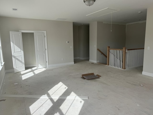 unfurnished room with attic access, visible vents, and baseboards