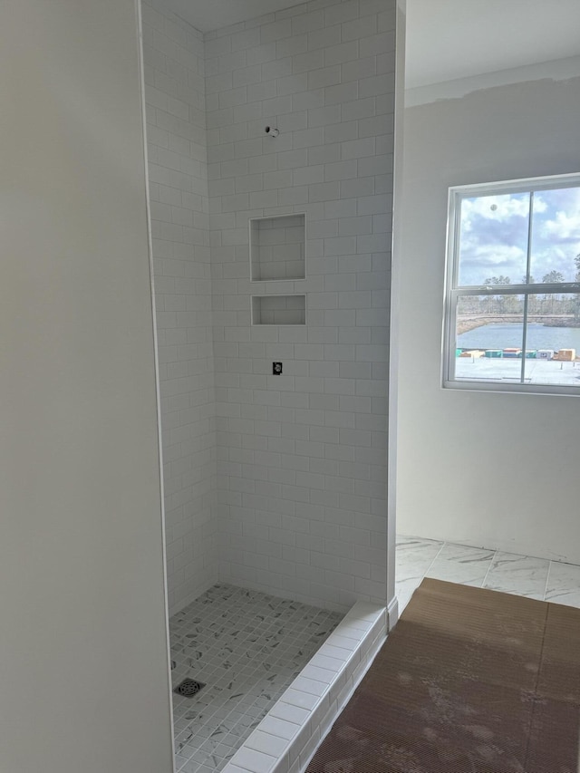 bathroom featuring marble finish floor and a shower stall