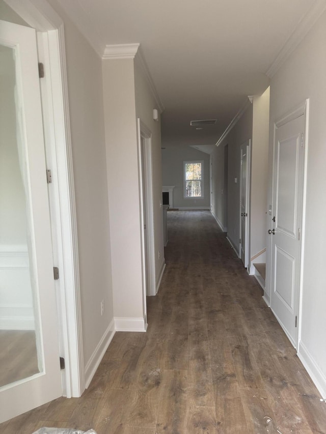 hallway featuring ornamental molding, dark wood-type flooring, visible vents, and baseboards