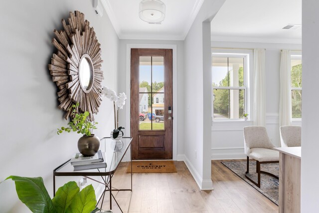 doorway featuring ornamental molding, visible vents, light wood-style floors, and baseboards