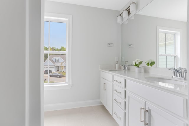 bathroom featuring double vanity, tile patterned flooring, a sink, and baseboards