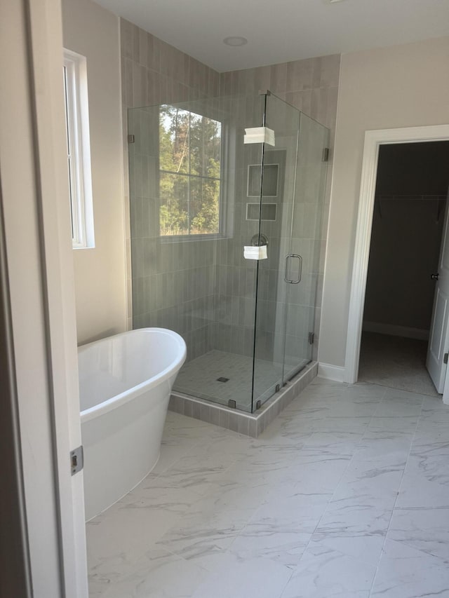 full bath with a freestanding tub, baseboards, marble finish floor, a shower stall, and a walk in closet