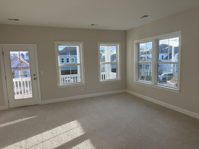 empty room featuring visible vents, light carpet, and baseboards