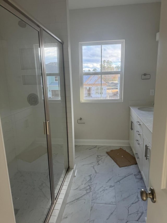 full bathroom with marble finish floor, a shower stall, baseboards, and vanity