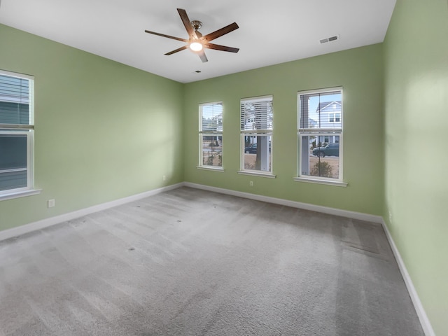 empty room with light carpet, a wealth of natural light, and ceiling fan