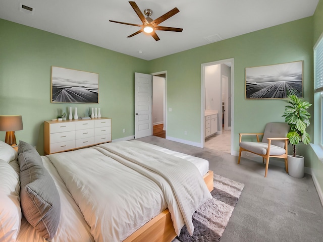 bedroom with ceiling fan, light carpet, and ensuite bath