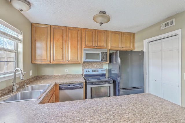 kitchen with appliances with stainless steel finishes, sink, and a textured ceiling