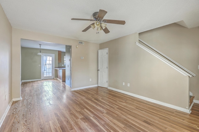 empty room featuring ceiling fan, a textured ceiling, and light wood-type flooring