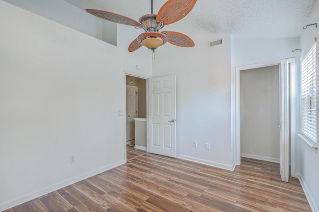 unfurnished bedroom featuring multiple windows, hardwood / wood-style floors, a textured ceiling, and ceiling fan