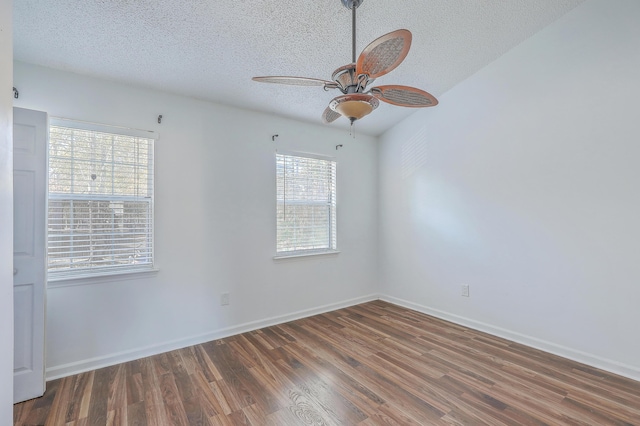 spare room featuring dark wood-type flooring, plenty of natural light, and a textured ceiling