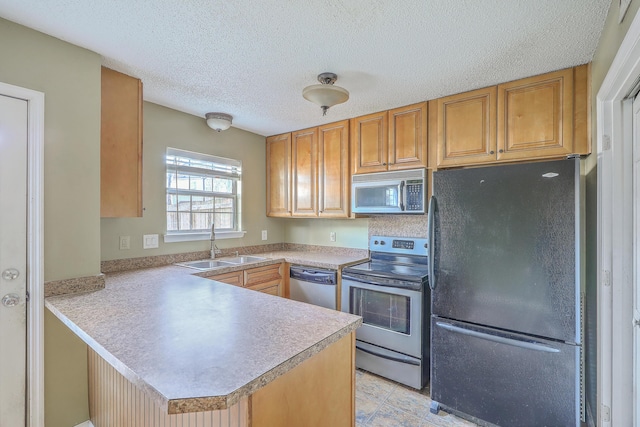 kitchen featuring stainless steel appliances, sink, a textured ceiling, and kitchen peninsula