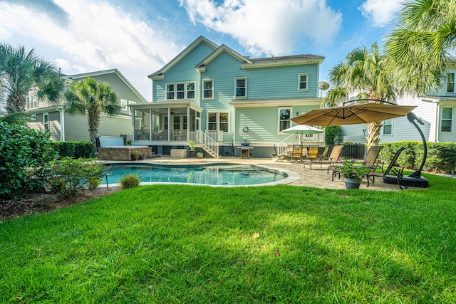 rear view of house with a lawn, a sunroom, and a patio area