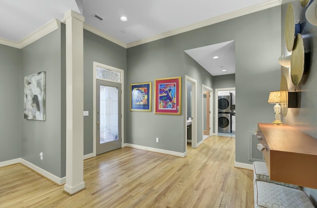 foyer entrance with baseboards, visible vents, and stacked washer / drying machine