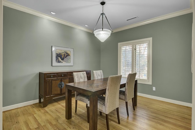 dining area with ornamental molding, light wood-type flooring, visible vents, and baseboards