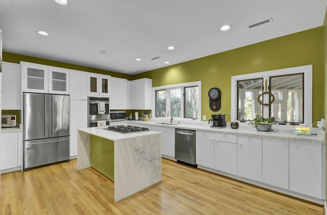 kitchen with a center island, light countertops, appliances with stainless steel finishes, white cabinetry, and a sink