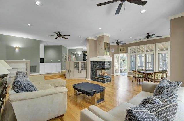 living area featuring wood finished floors, a multi sided fireplace, visible vents, and recessed lighting