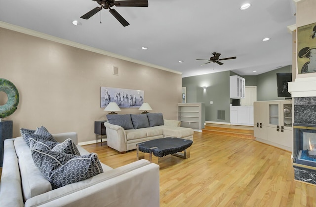 living area with light wood-style flooring, a premium fireplace, visible vents, and ornamental molding