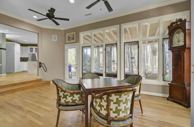 dining space with a healthy amount of sunlight, light wood-type flooring, visible vents, and crown molding