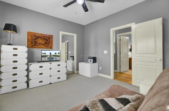 bedroom with a ceiling fan, light carpet, and baseboards