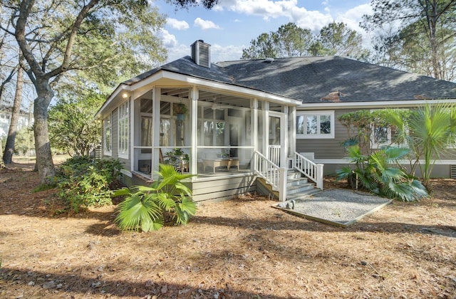 view of front of property with a shingled roof, a sunroom, and a chimney