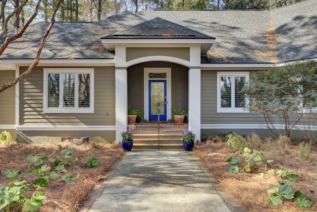 view of exterior entry with roof with shingles