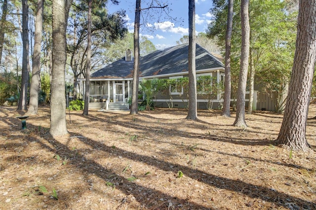 rear view of property featuring crawl space, a sunroom, and roof with shingles