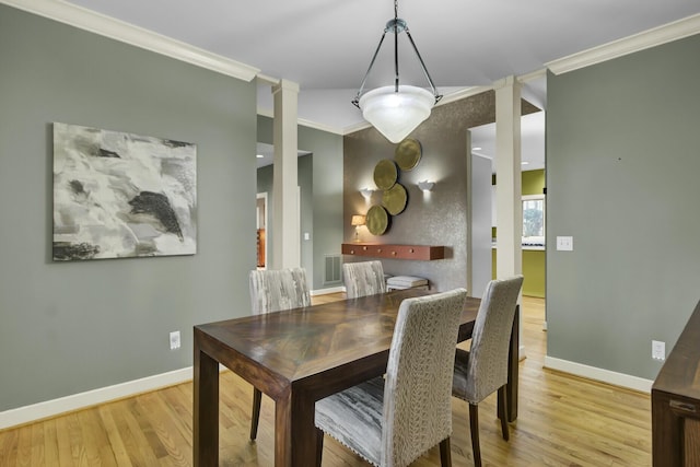 dining room with decorative columns, visible vents, baseboards, wood finished floors, and crown molding