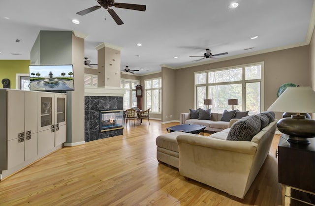 living area with crown molding, recessed lighting, light wood-type flooring, baseboards, and a tile fireplace