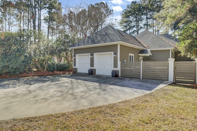 view of home's exterior featuring concrete driveway, roof with shingles, and fence