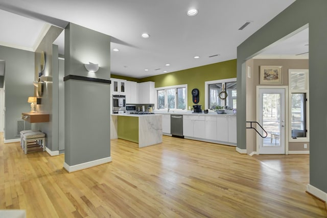 kitchen with visible vents, a kitchen island, appliances with stainless steel finishes, light countertops, and white cabinetry