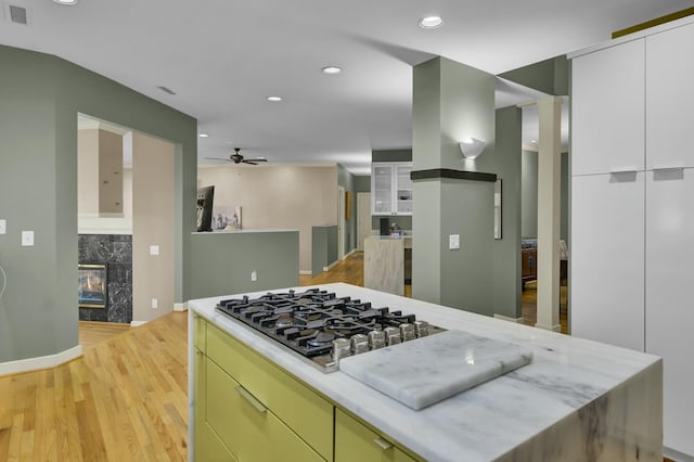 kitchen featuring recessed lighting, a premium fireplace, ceiling fan, gas cooktop, and light wood-type flooring