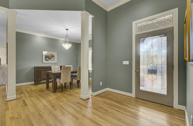 entrance foyer featuring light wood-style floors, decorative columns, ornamental molding, and baseboards