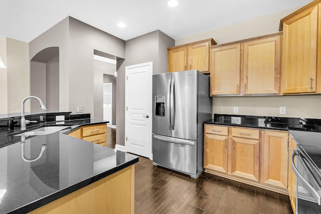 kitchen featuring dark stone counters, dark wood-type flooring, sink, kitchen peninsula, and stainless steel appliances