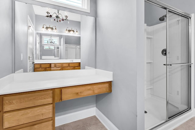 bathroom with an inviting chandelier, tile patterned floors, a shower with shower door, and vanity