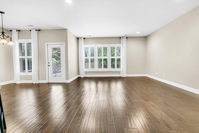 unfurnished living room with a chandelier and dark hardwood / wood-style flooring