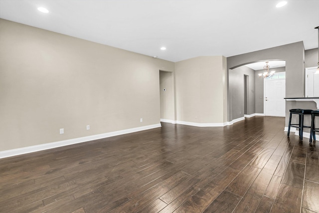 unfurnished living room featuring a notable chandelier and dark wood-type flooring