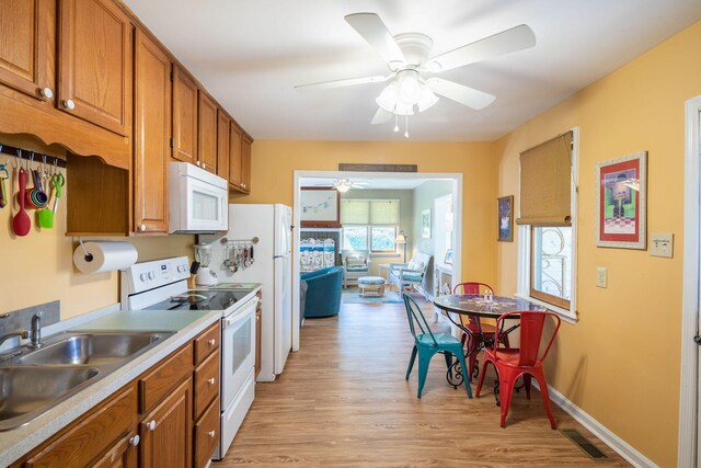 kitchen with white appliances, light hardwood / wood-style flooring, ceiling fan, and sink