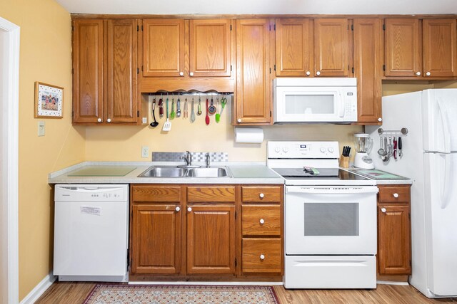 kitchen featuring sink, white appliances, and light wood-type flooring