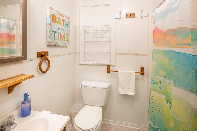 bathroom featuring tile patterned floors, toilet, walk in shower, and sink