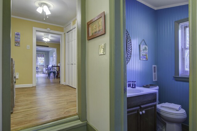 bathroom with hardwood / wood-style flooring, vanity, toilet, and crown molding