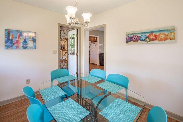 dining area with wood-type flooring and a notable chandelier